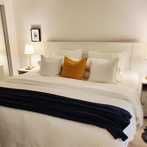 Una cama bien hecha con ropa blanca y un edredón azul oscuro.
