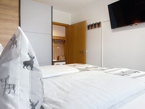 Une chambre d’hôtel avec un lit, une armoire, un miroir et un téléviseur fixé au mur.