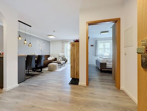 Ein modernes Wohnzimmer mit einer Couch, einem Couchtisch und dekorativen Accessoires. Eine Holztür führt in einen anderen Raum.
