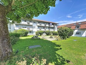Ein mehrstöckiges Gebäude mit Balkonen, einem grünen Innenhof und einem Baum.