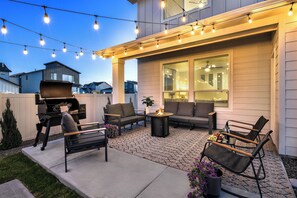An outdoor patio with a grill, seating, and string lights. - Sleeps 16 | Hot Tub +Game Garage + Kids' Play Loft (Meridian)