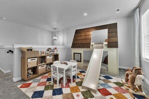 A child's playroom with a loft bed, a white table, and a colorful rug. - Sleeps 16 | Hot Tub +Game Garage + Kids' Play Loft (Meridian)