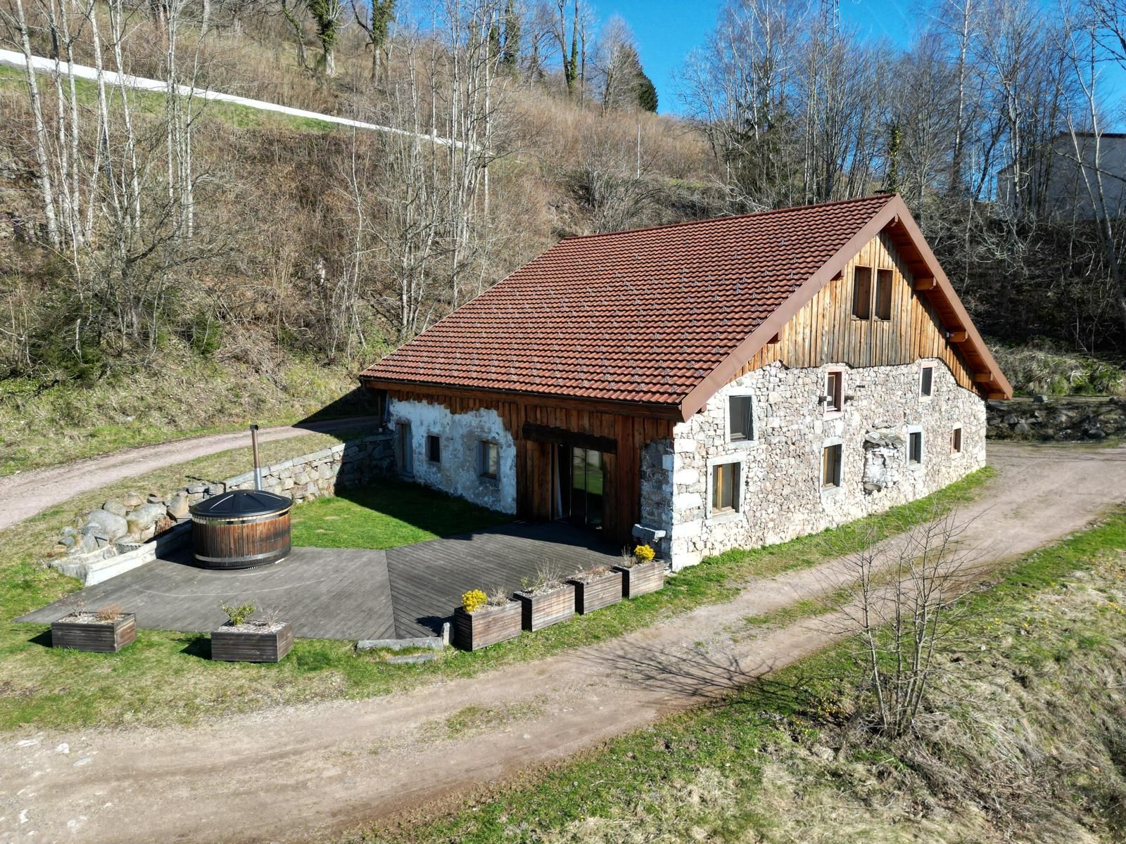 A rustic stone building with a sloped roof, wooden exterior, and a chimney.