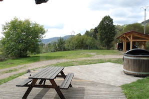 Ein Picknickplatz mit Holztisch und Bänken, einem Grill und einem Whirlpool.