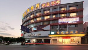 A multi-story hotel with illuminated signage, a visible restaurant on the ground floor, and a parking lot with cars. - Vienna Hotel (Guangzhou)