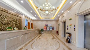 A hotel lobby with a reception desk, a chandelier, a marble floor, and an elevator. - Vienna Hotel (Guangzhou)