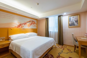Une chambre d’hôtel avec un grand lit, un bureau, une chaise, un tableau et un mur décoratif.