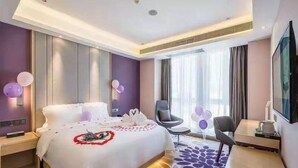 A modern hotel room with a large bed, bedside tables, a flat-screen TV, and a seating area with chairs. - Lavande Hotel (Chengdu)