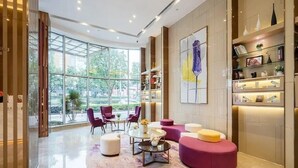 A modern lobby with a glass wall, seating area, and a bookshelf. - Lavande Hotel (Chengdu)