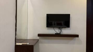 Un dormitorio moderno con una cama, un televisor en la pared, una mesita de noche y un espejo.