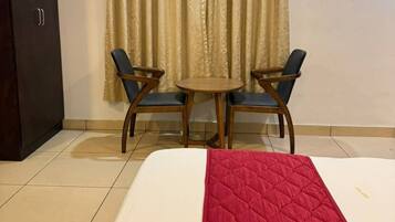 Una habitación de hotel con una cama, una mesita pequeña con dos sillas y un armario.