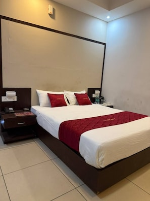 Ein Hotelzimmer mit einem großen Bett, einem Nachttisch mit Telefon und Lampe sowie einer Wandleuchte.