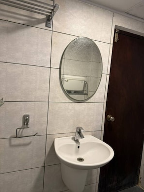 Ein Badezimmer mit einem weißen Waschbecken, einem Spiegel und einem Handtuchhalter.