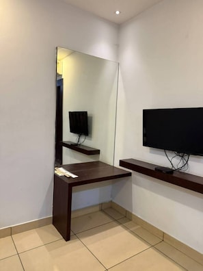 Ein Zimmer mit einem dunklen Holztisch, einem an der Wand befestigten Flachbildfernseher und einem wandmontierten Spiegel.