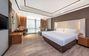 Habitació d'hotel moderna amb un llit gran, un escriptori, una cadira i una televisió.