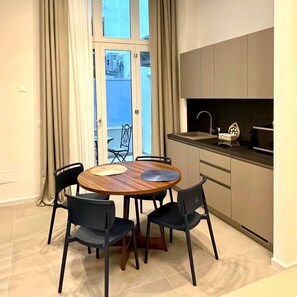 A modern kitchen with a dining area, featuring a round table with chairs, a built-in oven, and a view through a glass door. - Vrbo Property (Bari)