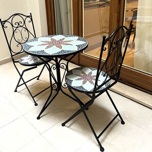 A round table with a mosaic top and two chairs with a similar design. - Vrbo Property (Bari)