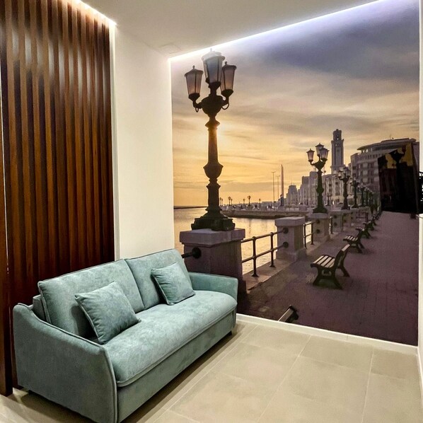 A room with a sofa, a wall mural of a cityscape, and a lamp. - Vrbo Property (Bari)
