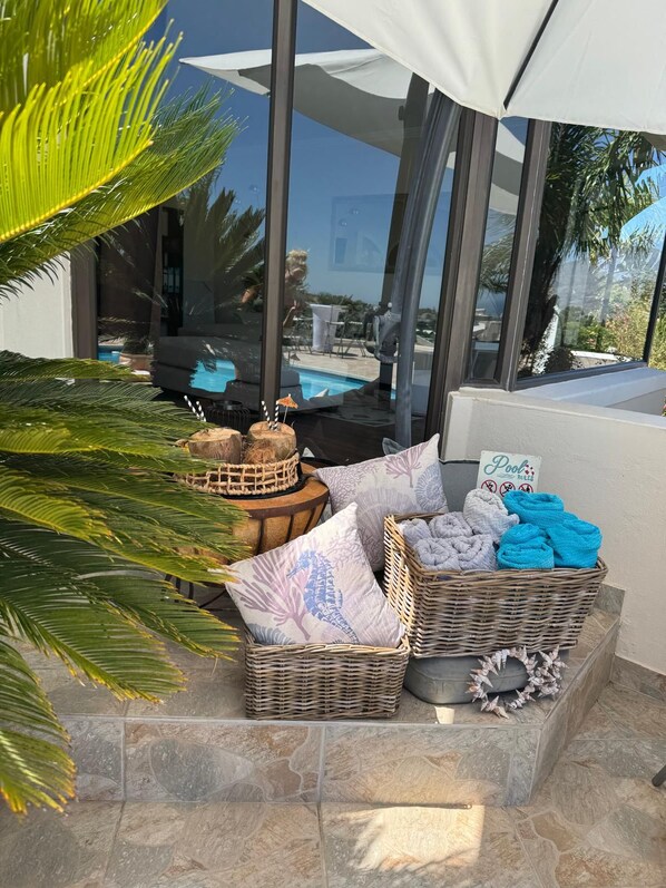 A poolside area with wicker baskets containing towels and a sign indicating pool rules.