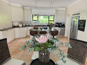 A modern kitchen with white cabinetry, a central island, and a dining area with two chairs.
