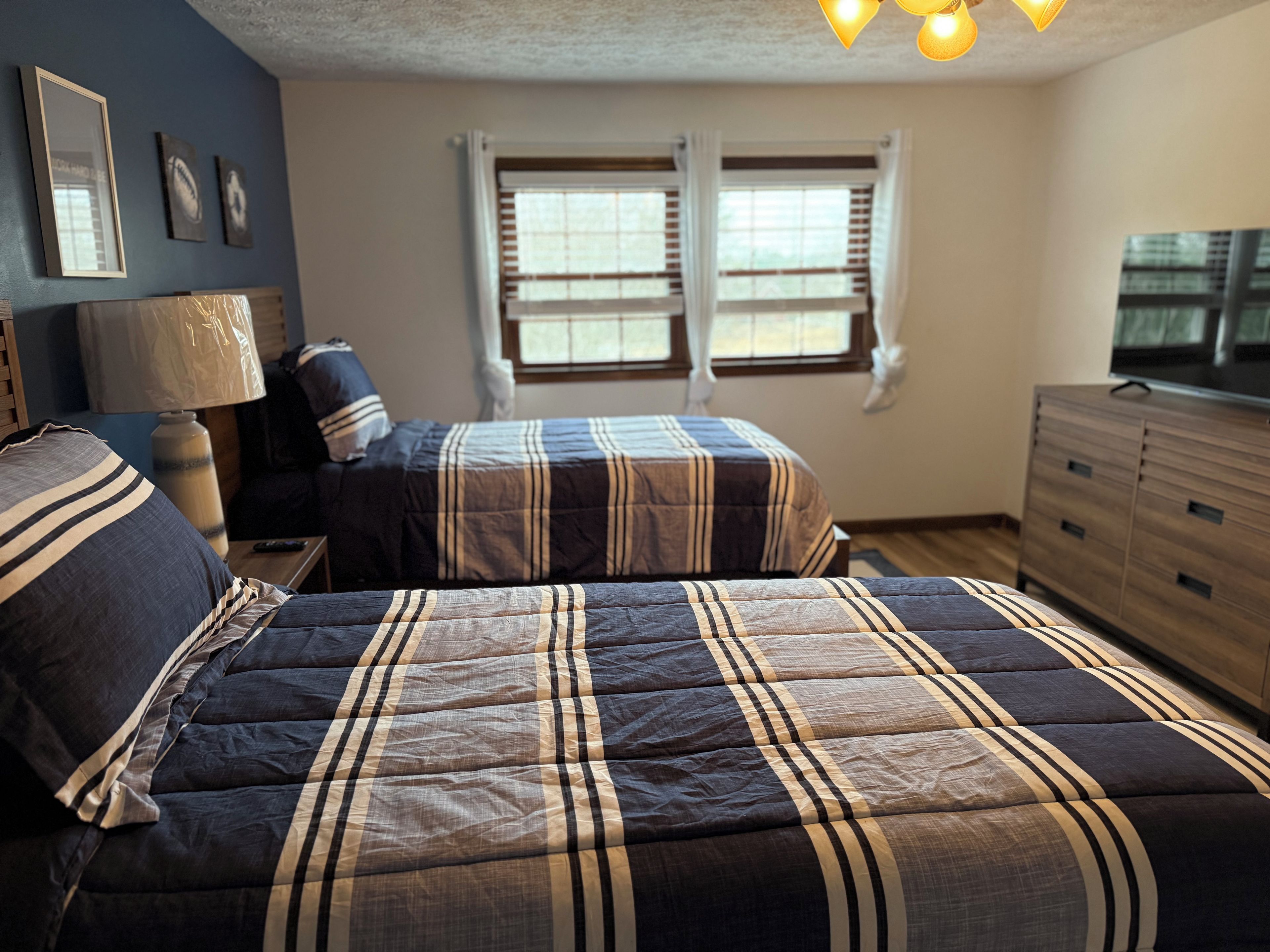 Un dormitorio con dos camas, un aparador, una lámpara y un televisor.