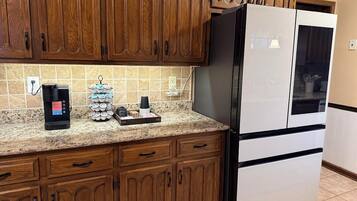 Una cocina con armarios de madera, un refrigerador de acero inoxidable y una cafetera sobre la encimera.