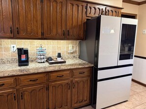Una cocina con armarios de madera, un refrigerador de acero inoxidable y una cafetera sobre la encimera.