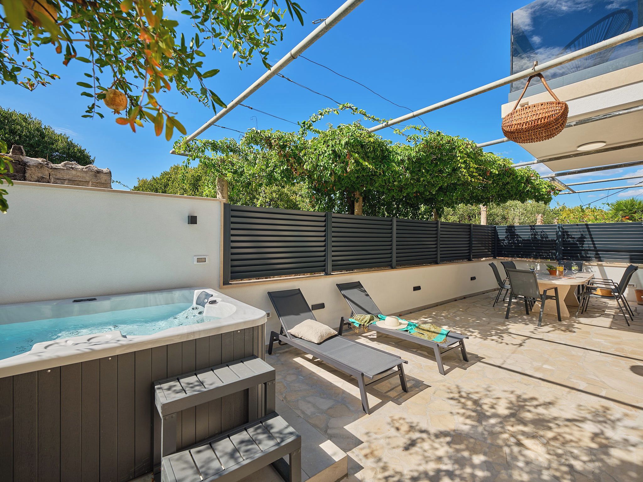 Eine Außenpatio mit Whirlpool, Liegestühlen und einem Tisch mit Stühlen.