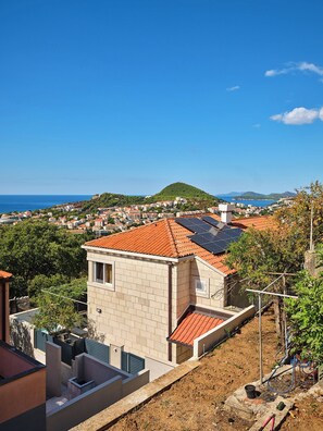 A residential area with terracotta-tiled roofs, a clear blue sky, and a view of the sea. - Hedera Estate, House Hedera II (Dubrovnik)