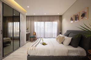 Ein modernes Schlafzimmer mit einem großen Bett, einer Schiebetür aus Glas, einem Sessel und Bildern an der Wand.