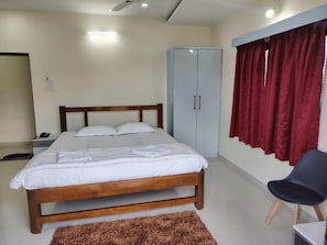 Ein Schlafzimmer mit einem Bett, einem Kleiderschrank, einem Sessel und einem Teppich.