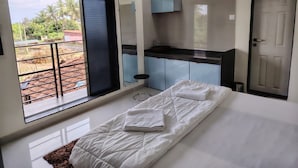Une chambre d’hôtel comprenant un lit, une petite kitchenette, une salle de bain et un balcon avec vue sur l’extérieur.