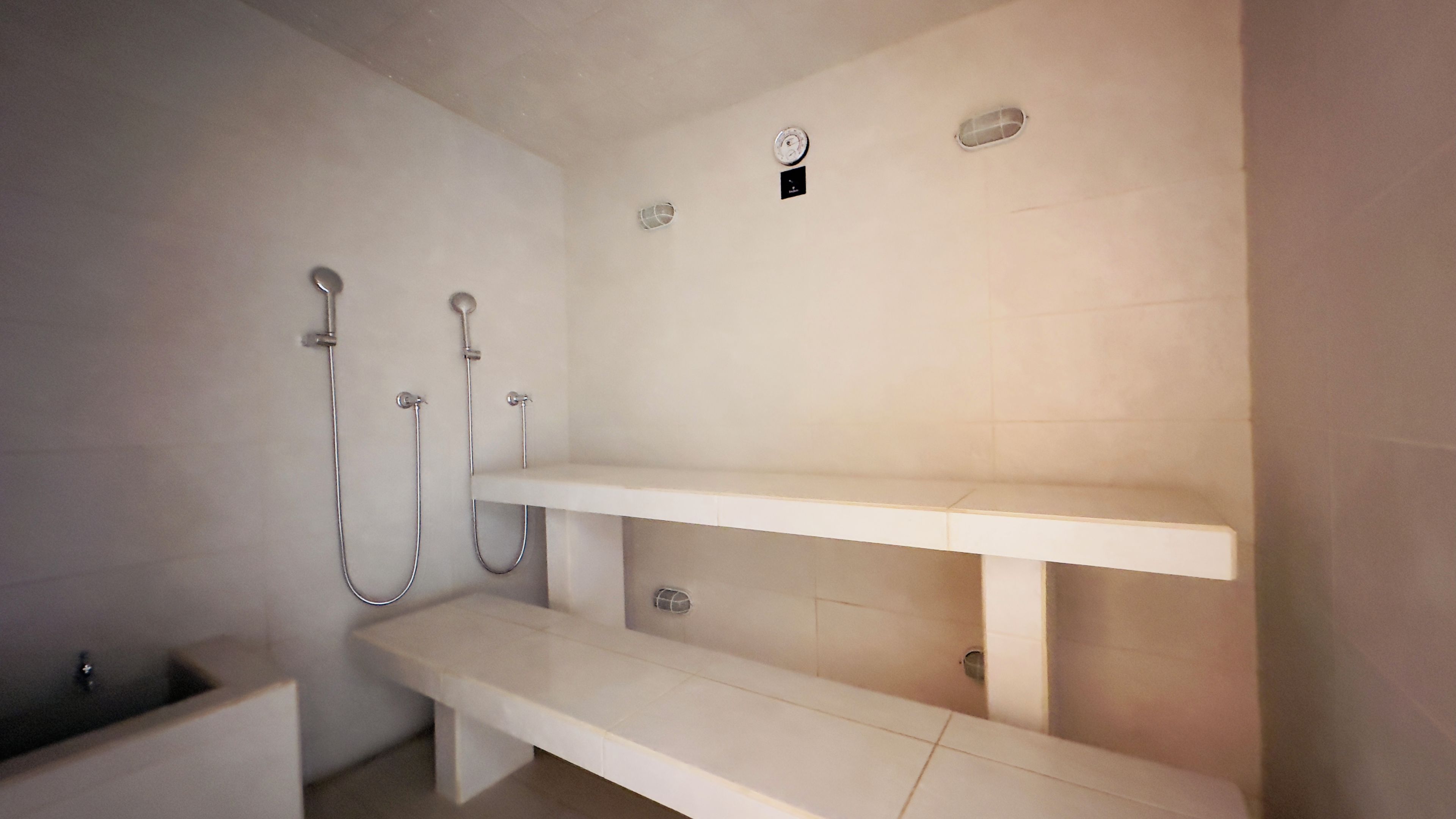 Un baño con ducha, inodoro y un banco.