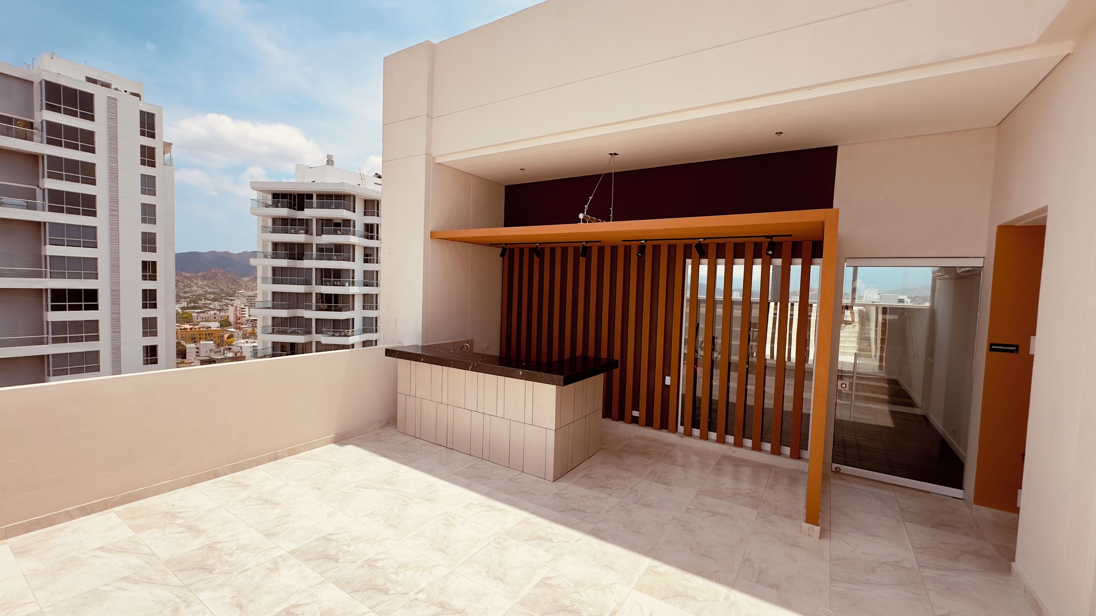 Un balcón con cocina, una puerta corredera y vistas a la ciudad.