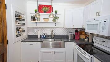 A compact kitchen with white cabinets, a stainless steel sink, a microwave, and a built-in oven.