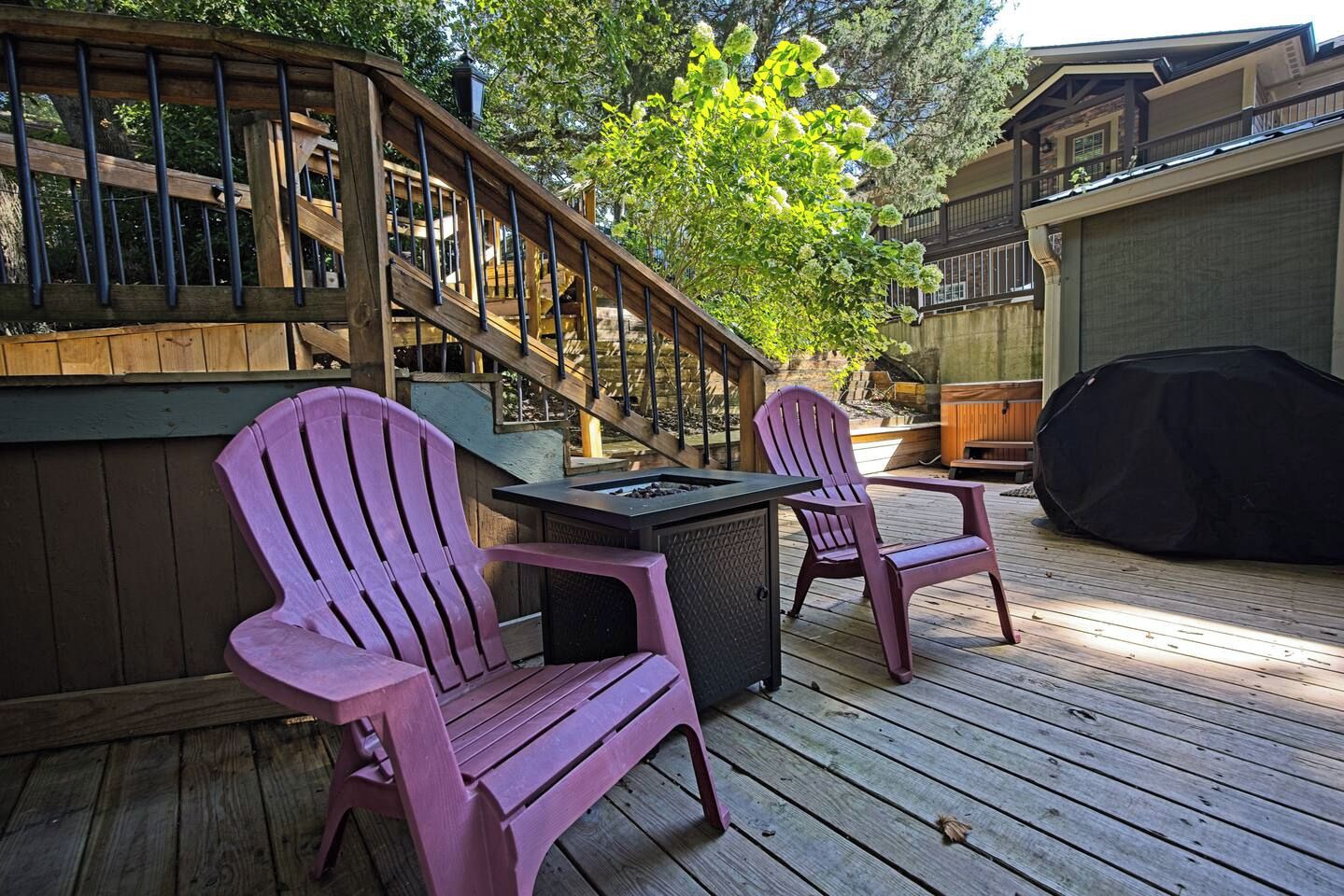 A wooden deck with two Adirondack chairs, a barbecue grill, and a fire pit.