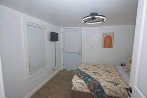 A bedroom with a bed, a door, a wall-mounted TV, and a ceiling light fixture. - Messer Manor - Downtown, Walk to Shops (Blue Ridge)