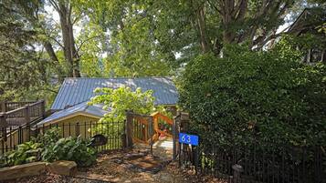 A gated entrance with a blue sign, a metal gate, and a pathway leading to a building with a blue roof.