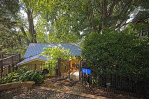 A gated entrance with a blue sign, a metal gate, and a pathway leading to a building with a blue roof. - Messer Manor - Downtown, Walk to Shops (Blue Ridge)