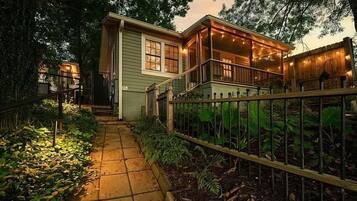 A house with a covered porch, a pathway leading to the entrance, and a fenced garden area.