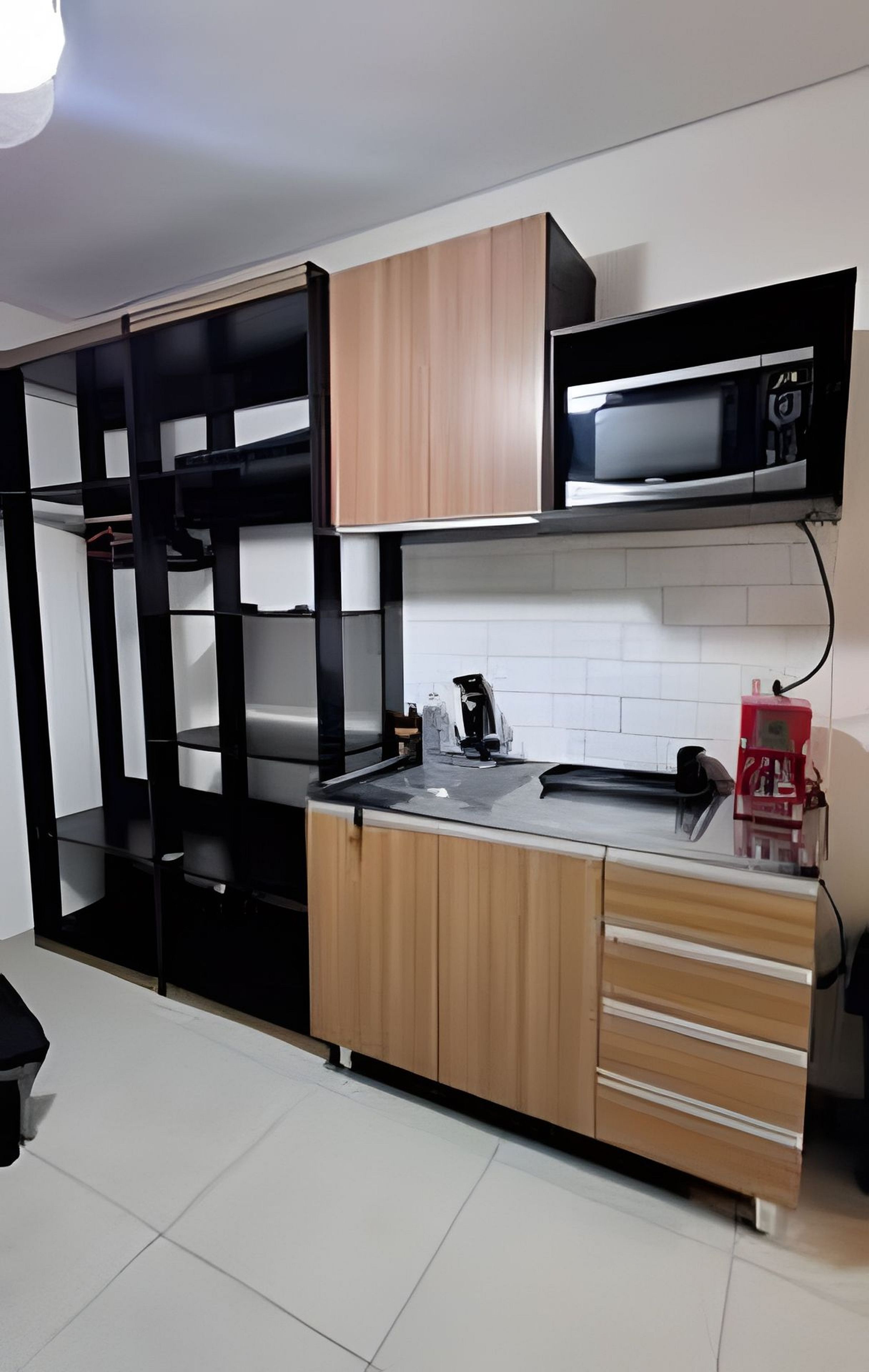 Een kleine keuken met een magnetron, een spoelbak en houten kastjes.