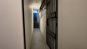 A narrow hallway with a metal gate, a staircase, and a ceiling light. - Salles Residence Barra Funda (São Paulo)