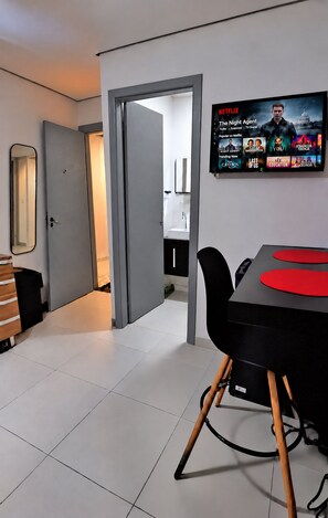 A modern living room with a flat-screen TV mounted on the wall displaying a Netflix interface. - Salles Residence Barra Funda (São Paulo)