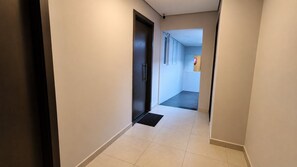 A hallway with a door, a doormat, and a tiled floor.