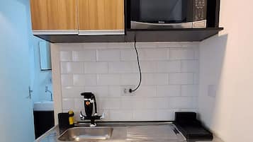 Una cocina moderna con armarios de madera, un lavamanos de acero inoxidable y un microondas integrado.