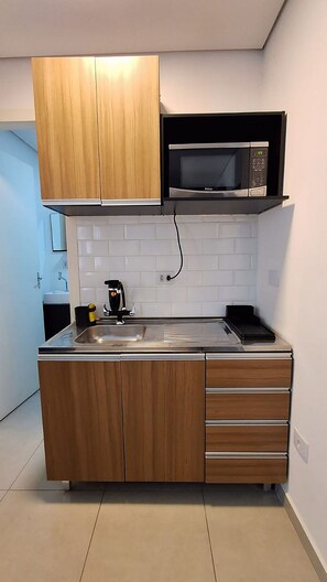A modern kitchen with wooden cabinets, a stainless steel sink, and a built-in microwave.