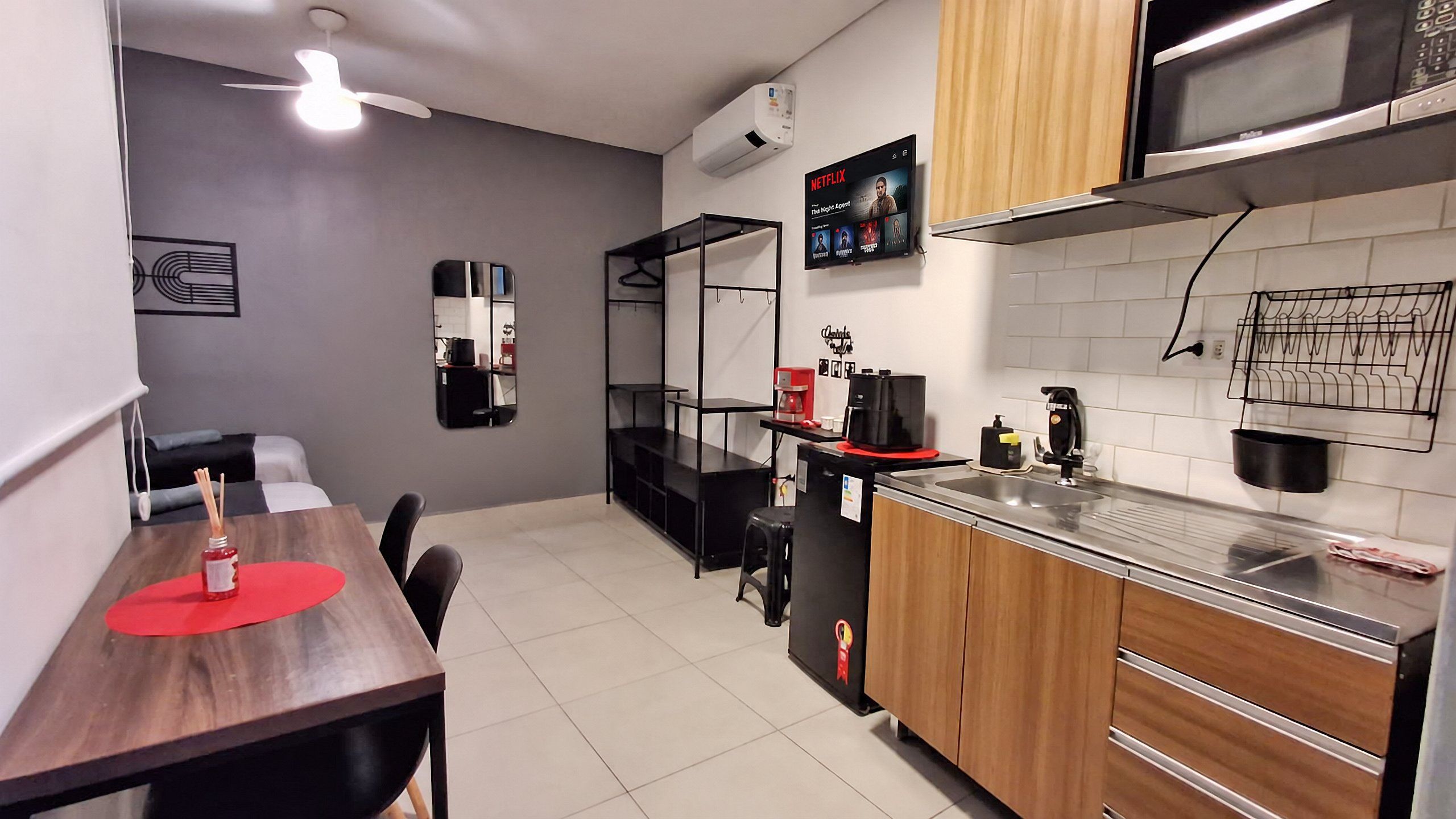 A compact kitchen with a dining area, a microwave, a coffee machine, and a refrigerator.