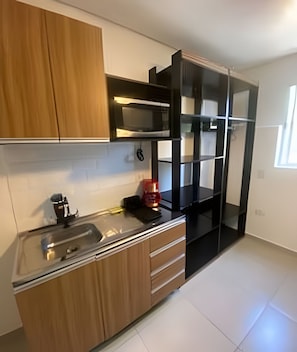 A kitchen with wooden cabinets, a stainless steel sink, and a black countertop.