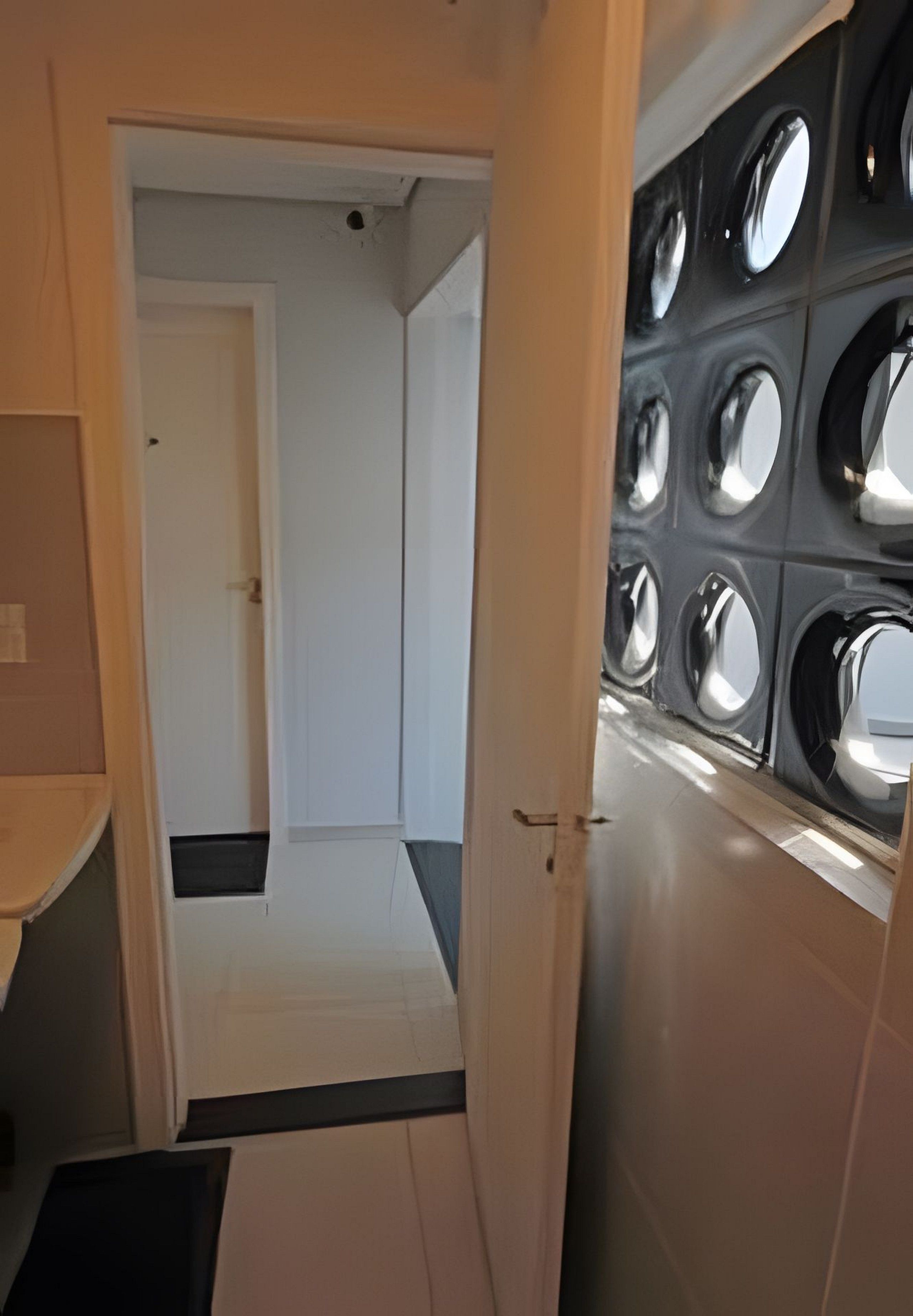 Een gang die leidt naar een kamer met een groot raam en een deur.