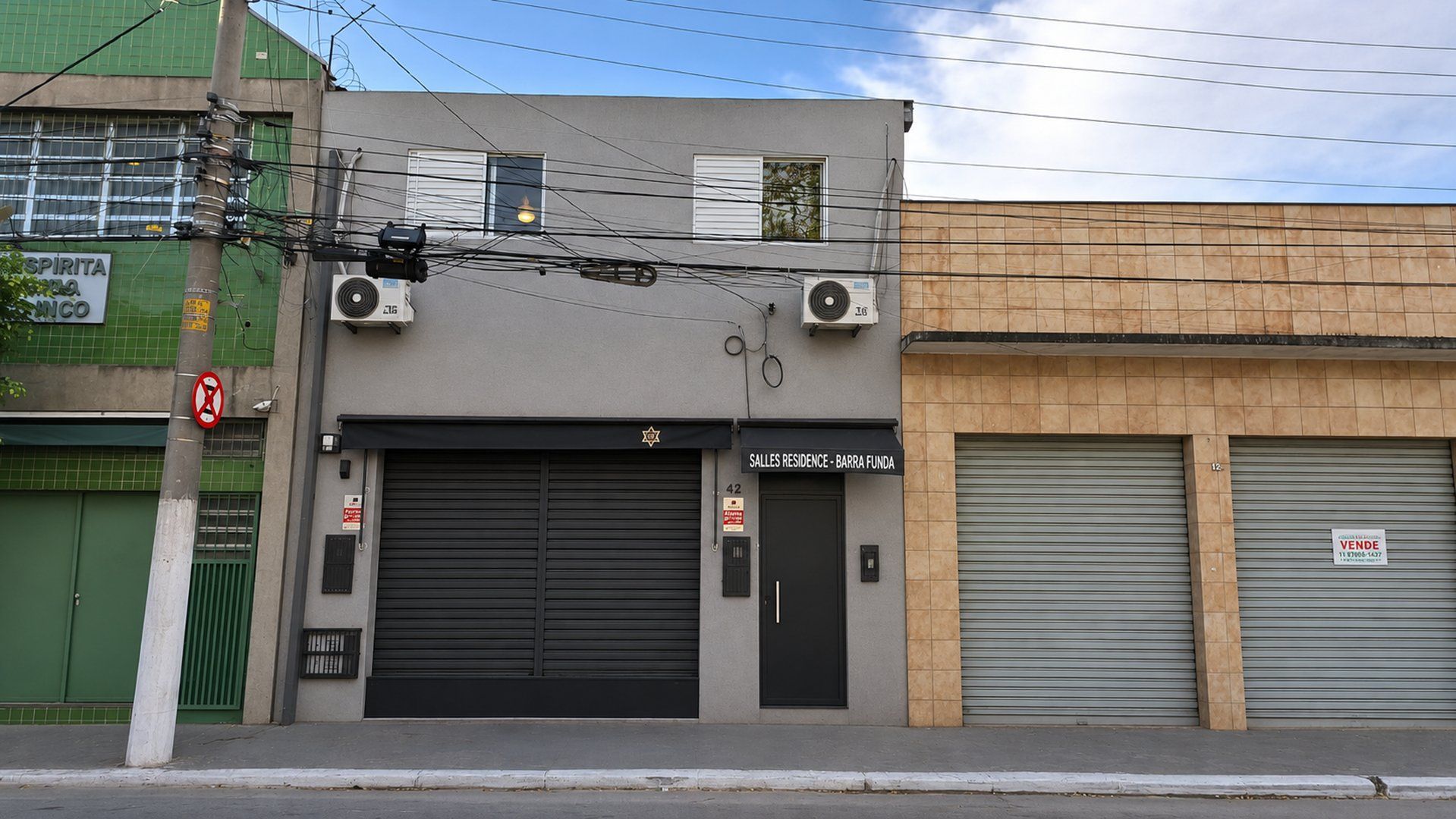 A building with closed shutters, a sign for 'Salles Residence - Barra Funda', and a 'No Parking' sign.
